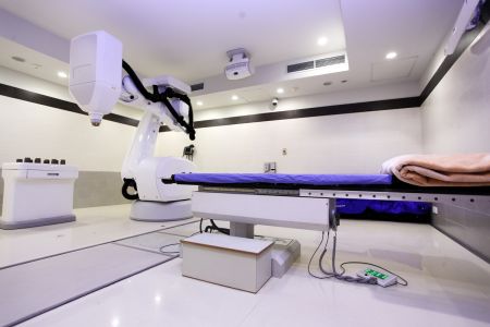 Untersuchungsraum mit Bestrahlungsgerät und Patientenliege.